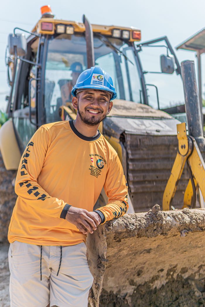 Smiling construction worker poses beside a bulldozer on a sunny day