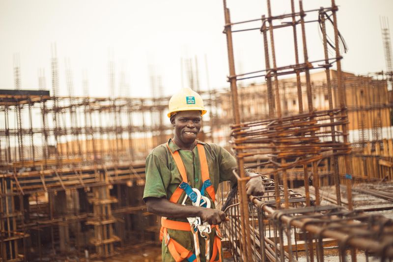 Smiling construction worker wearing a helmet at a site in Kitgum Matidi, Uganda