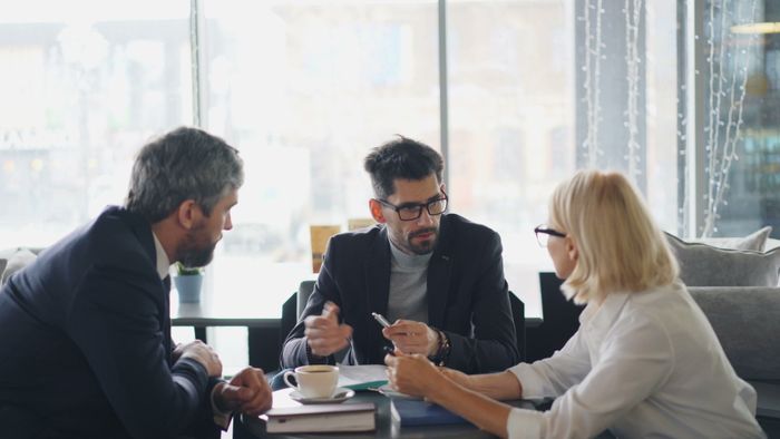 Three business people sitting at a table talking