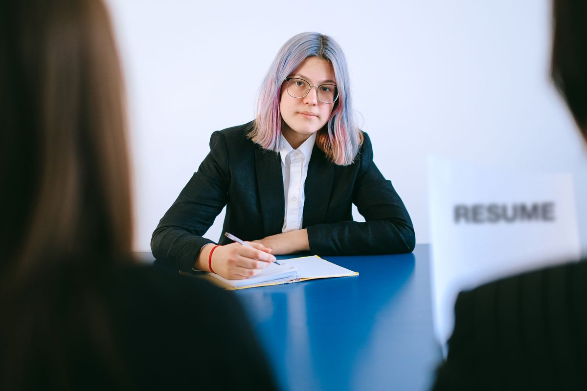 A young woman with dyed hair takes notes during a job interview