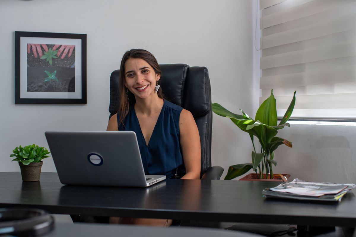 Smiling businesswoman seated at desk with laptop in a modern office