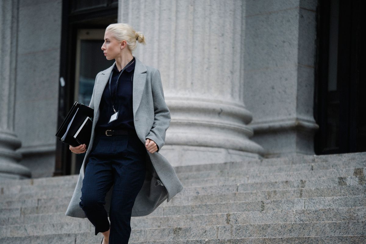 Serious female lawyer in elegant outfit holding folders