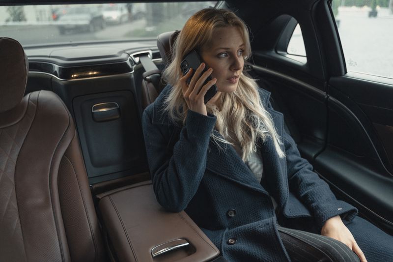 Young businesswoman talking on phone in a luxury car