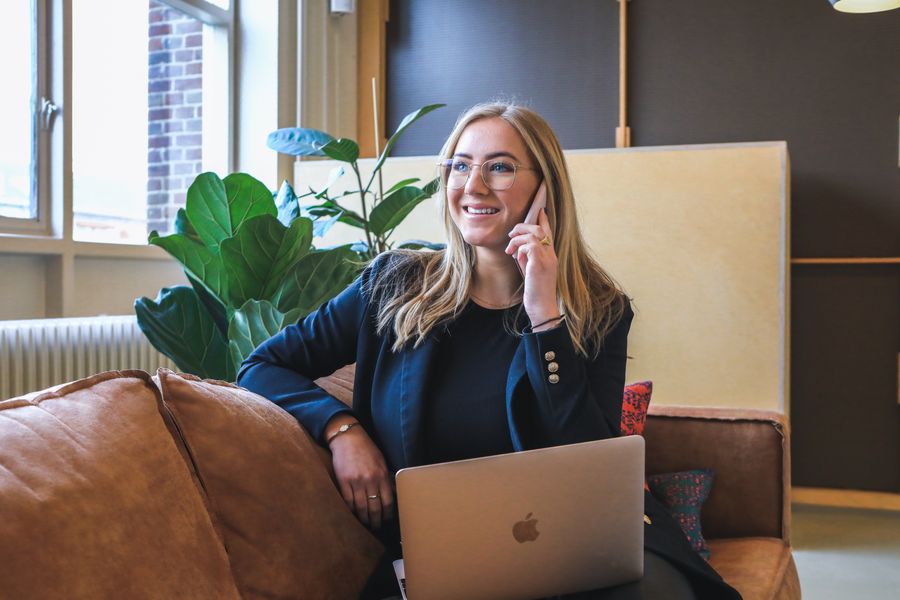 Smiling woman multitasking with phone call and laptop in stylish office