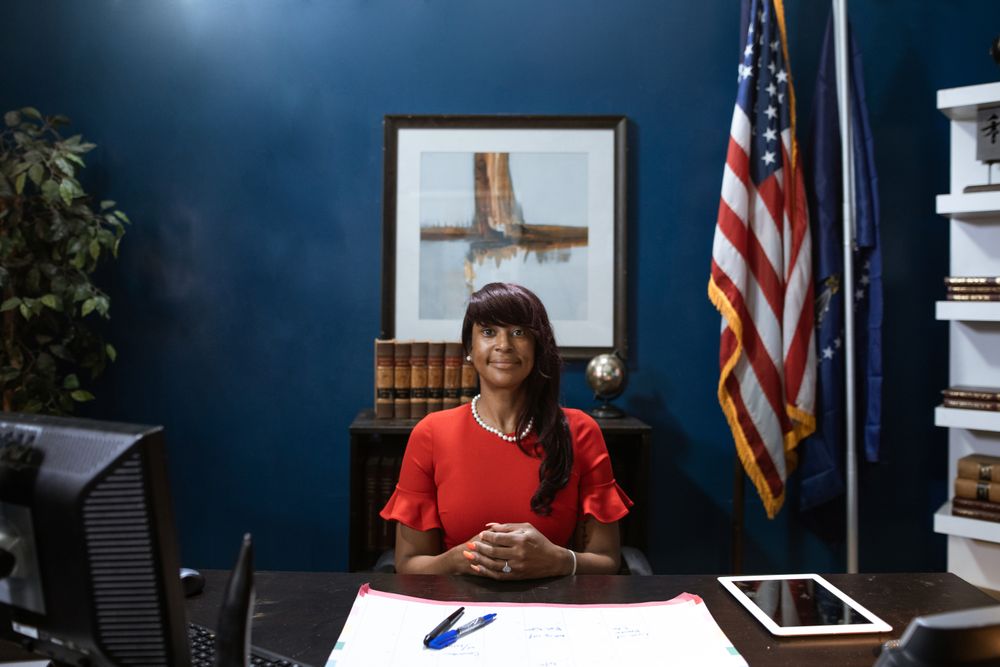 Confident businesswoman sitting in office, smiling at desk with American flags