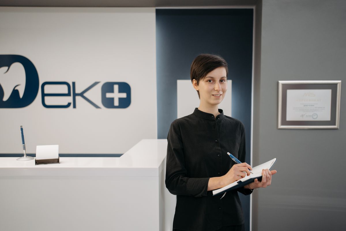 Smiling woman holding a notebook at a modern dentist office reception area