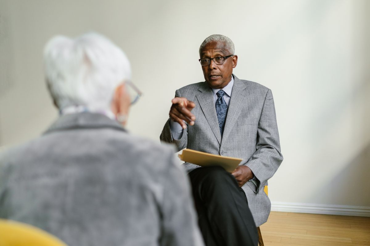Two senior adults in a business meeting indoors, discussing important matters