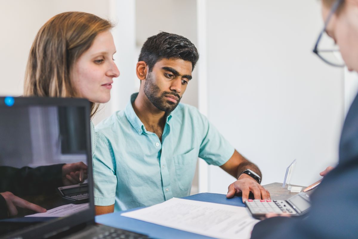 A young couple in discussion with a real estate agent in a modern office setting