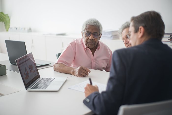 An elderly couple in conversation with a professional advisor