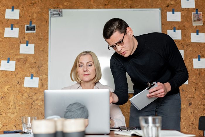 Two colleagues collaborating at a work desk in a modern office setting